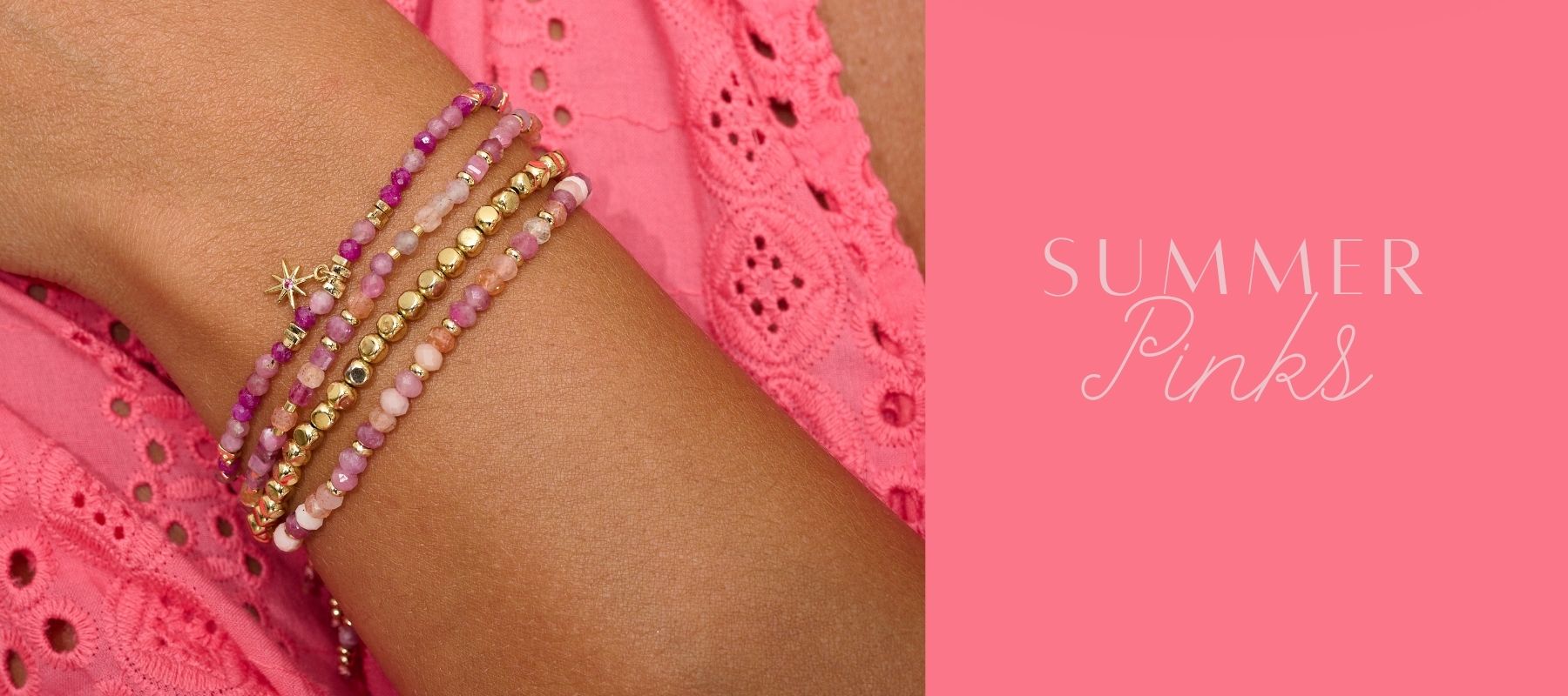 A close-up of a woman’s wrist adorned with layered Boho Betty gemstone bracelets in shades of pink, magenta and gold, featuring delicate beads and a tiny star charm. She wears a vibrant pink eyelet dress, evoking a joyful, sun-drenched summer vibe.