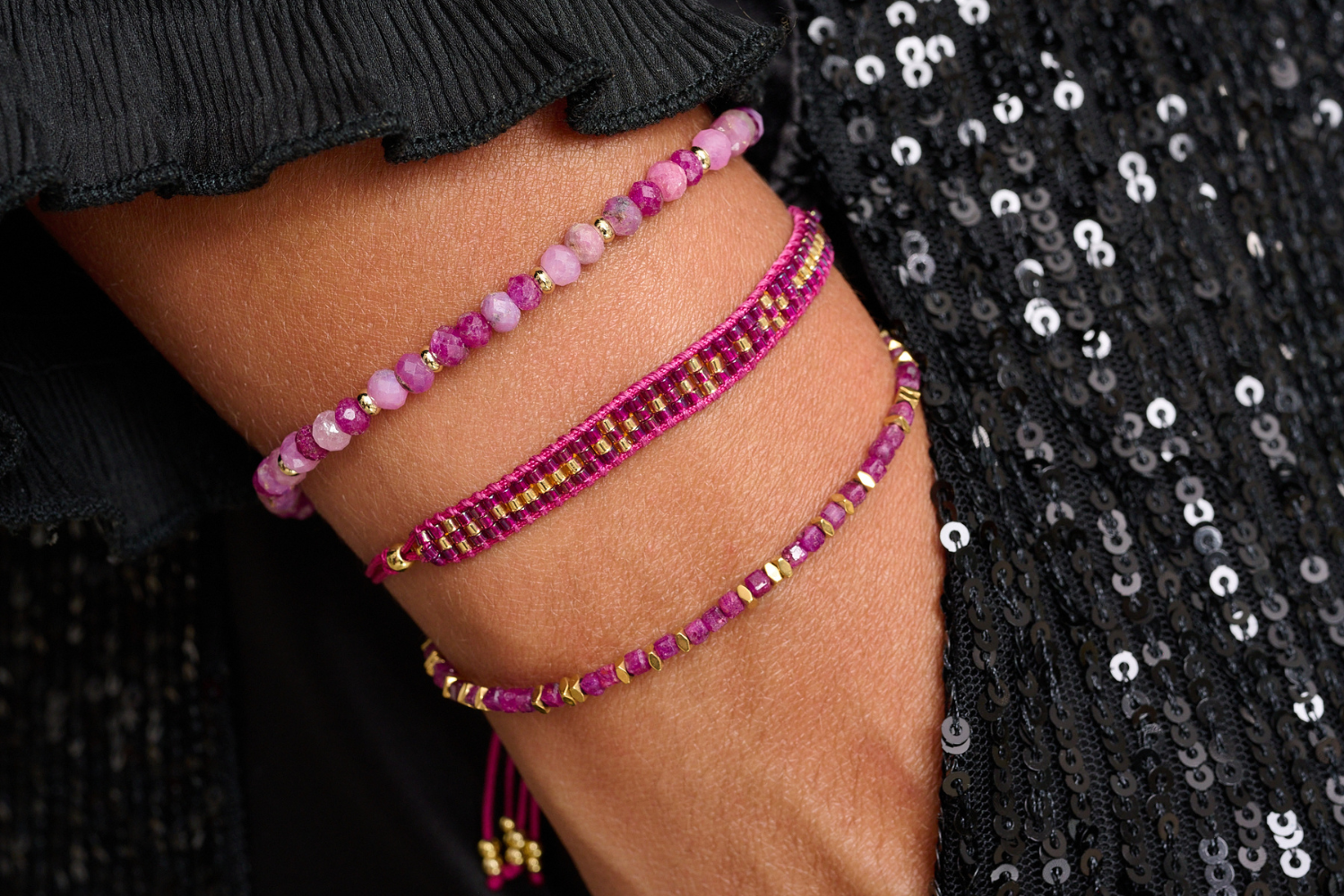 Vik Ruby Gold Bracelet Stack styled on the models wrist, showcasing vibrant ruby stones, gold accents, and woven textures for a bold layered look.